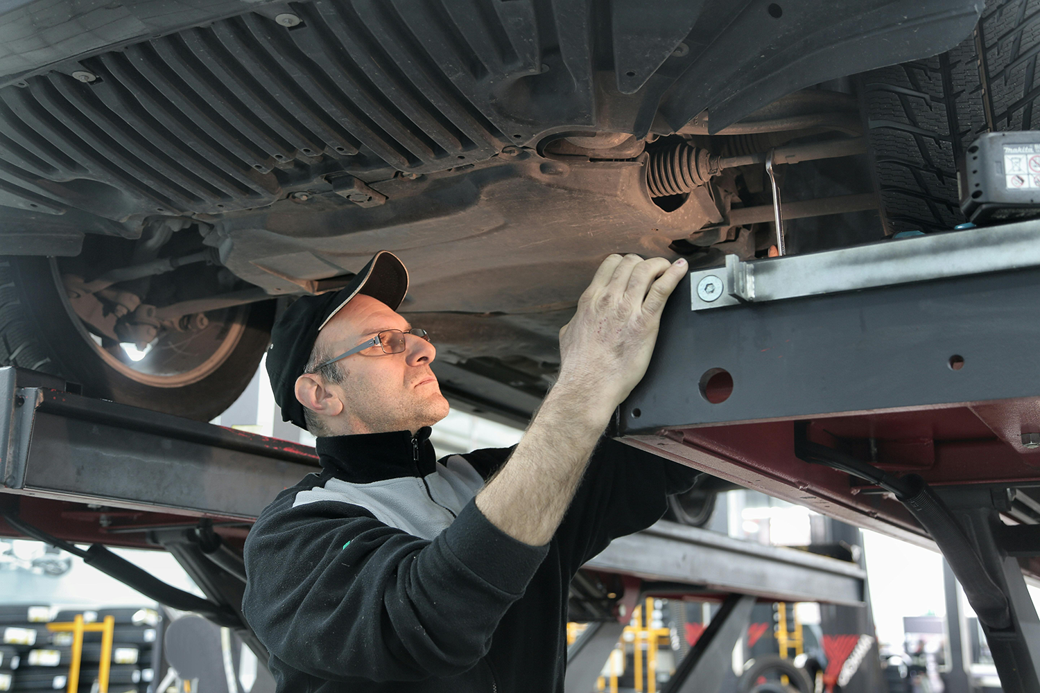 Auto mechanic working under a vehicle on a lift in a repair shop